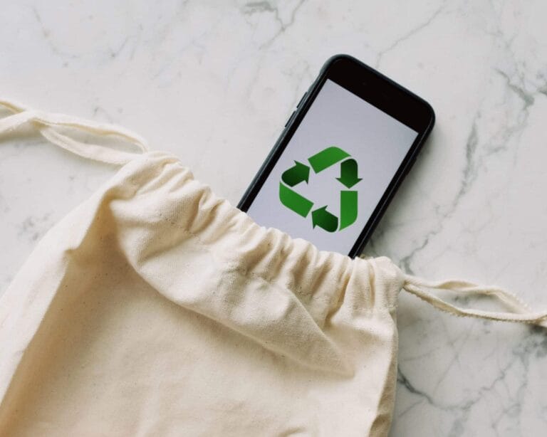 Concept écologique avec un smartphone affichant un symbole de recyclage dans un sac en coton