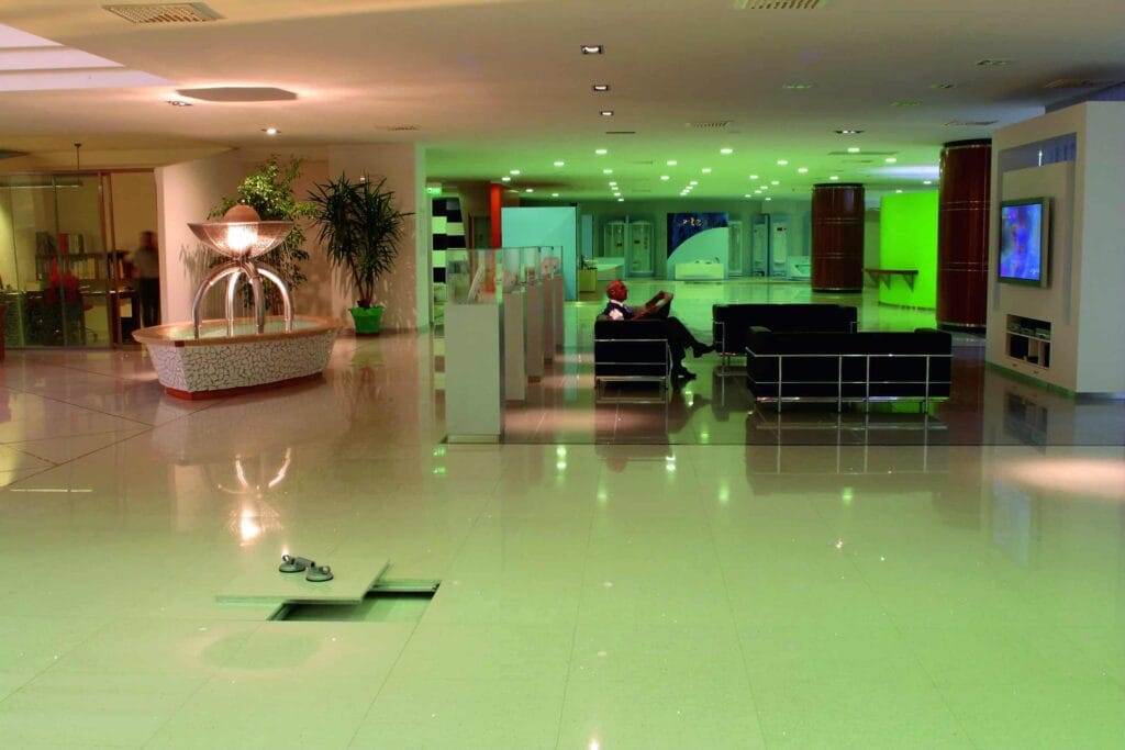 Intérieur spacieux et moderne avec des sols brillants, une fontaine centrale, des sièges lounge et une ambiance verte