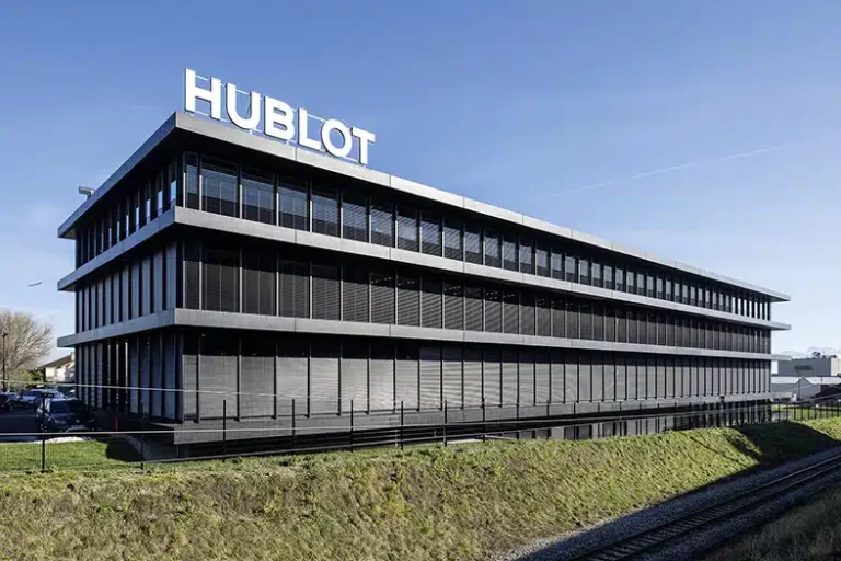 Le bâtiment du siège de Hublot avec une façade en verre noir élégante, situé près des voies ferrées