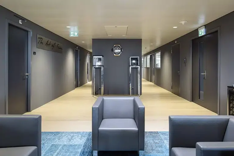 Un couloir minimaliste dans un espace de bureau haut de gamme, avec une décoration contemporaine, un éclairage doux et des sièges confortables pour les visiteurs