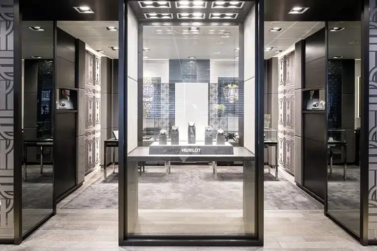 Une boutique de montres luxueuse présentant des montres haut de gamme exposées dans une vitrine en verre élégante et bien éclairée, avec des intérieurs raffinés et une marque visible