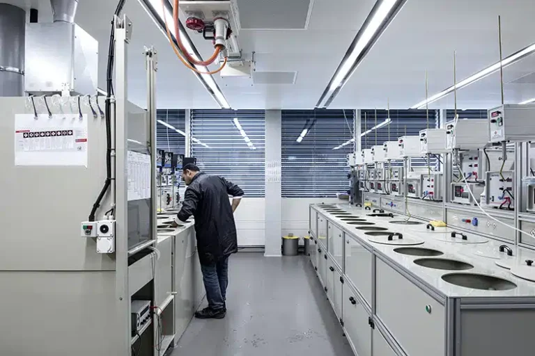 Un environnement de laboratoire avec un employé en manteau noir supervisant des équipements industriels, entouré de machines avancées et de postes de travail