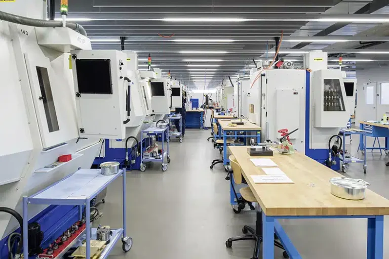 Un long couloir dans un atelier industriel bordé d'outils d'usinage et de bancs de travail bleus, mettant en valeur la précision et l'organisation