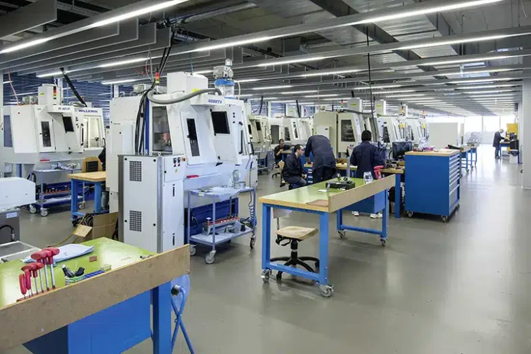 Un espace de travail industriel moderne avec des rangées d'outils d'usinage avancés, des stations de travail bleues et des travailleurs engagés dans des tâches de fabricatio