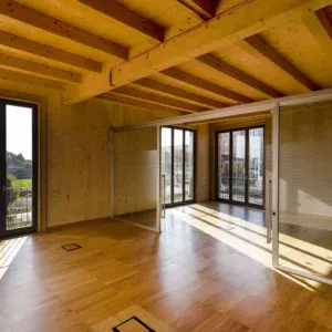 Intérieur de bureau moderne avec murs et sol en bois, grandes fenêtres et cloison vitrée séparant l’espace