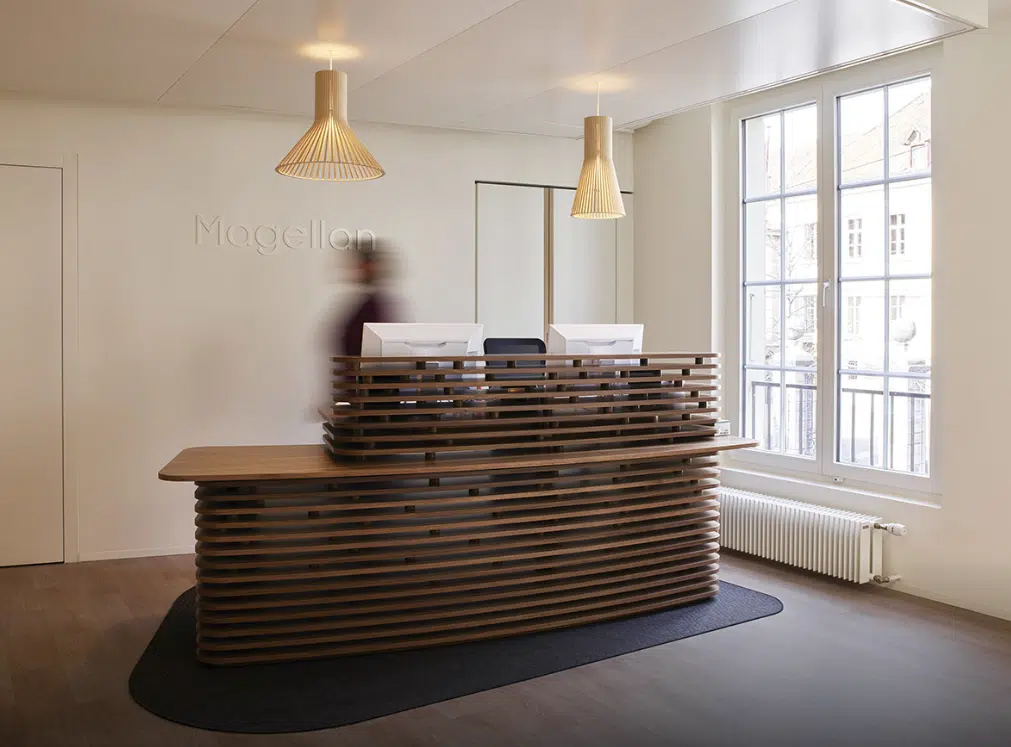 Zone de réception avec un bureau en bois, des lumières suspendues et une grande fenêtre pour la lumière naturelle