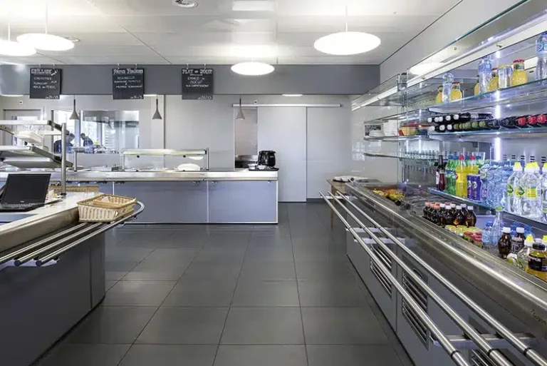 Une cafétéria propre et moderne avec des présentoirs de nourriture bien rangés et des réfrigérateurs de boissons