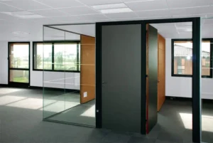 Un espace de bureau avec une porte noire et des cloisons vitrées transparentes, permettant à la lumière naturelle de circuler