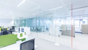 Un bureau high-tech avec des cabines vitrées, du mobilier blanc et des séparateurs verts pour un look frais et moderne