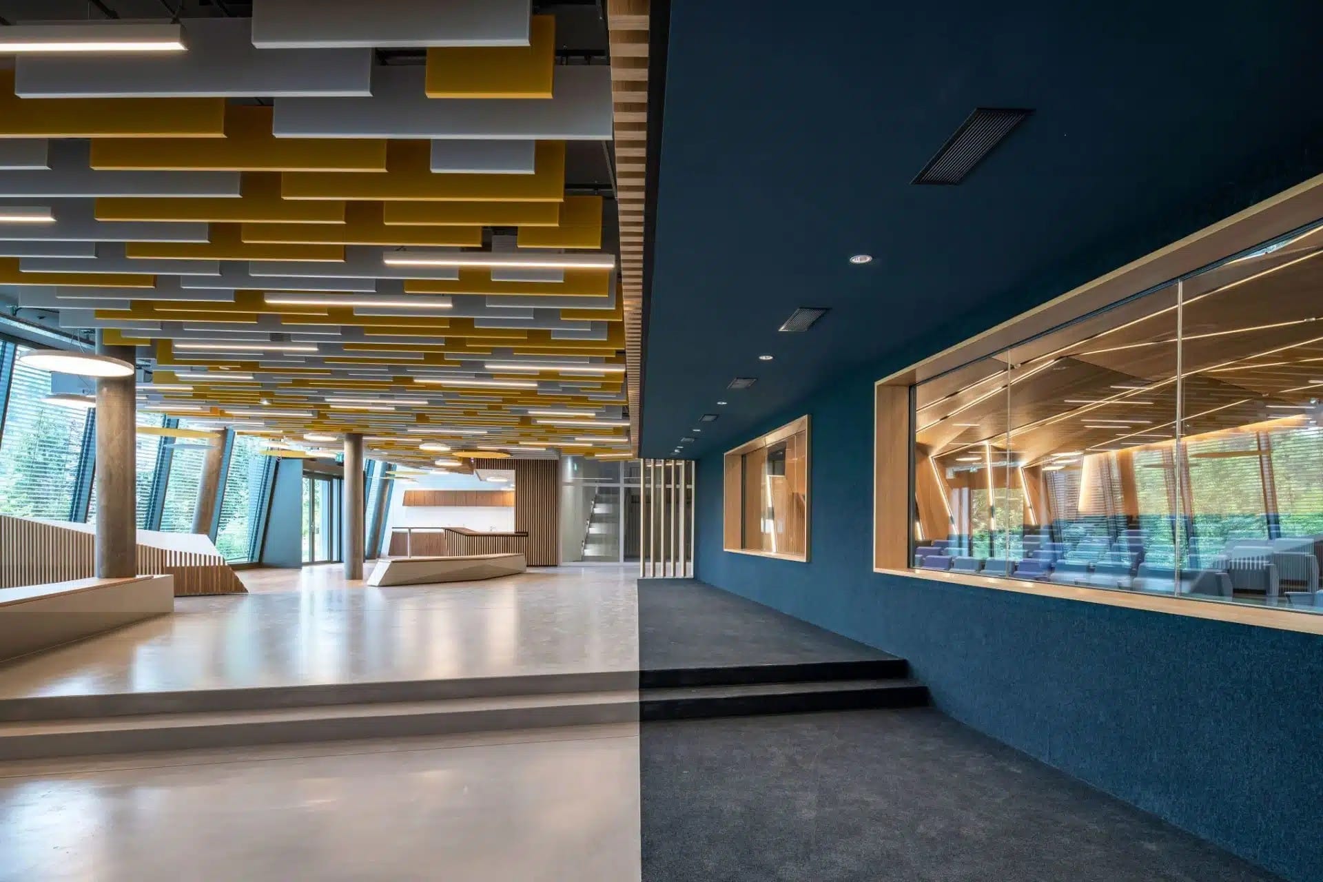 Hall moderne avec un design de plafond acoustique unique en jaune et blanc, combiné à des accents en bois
