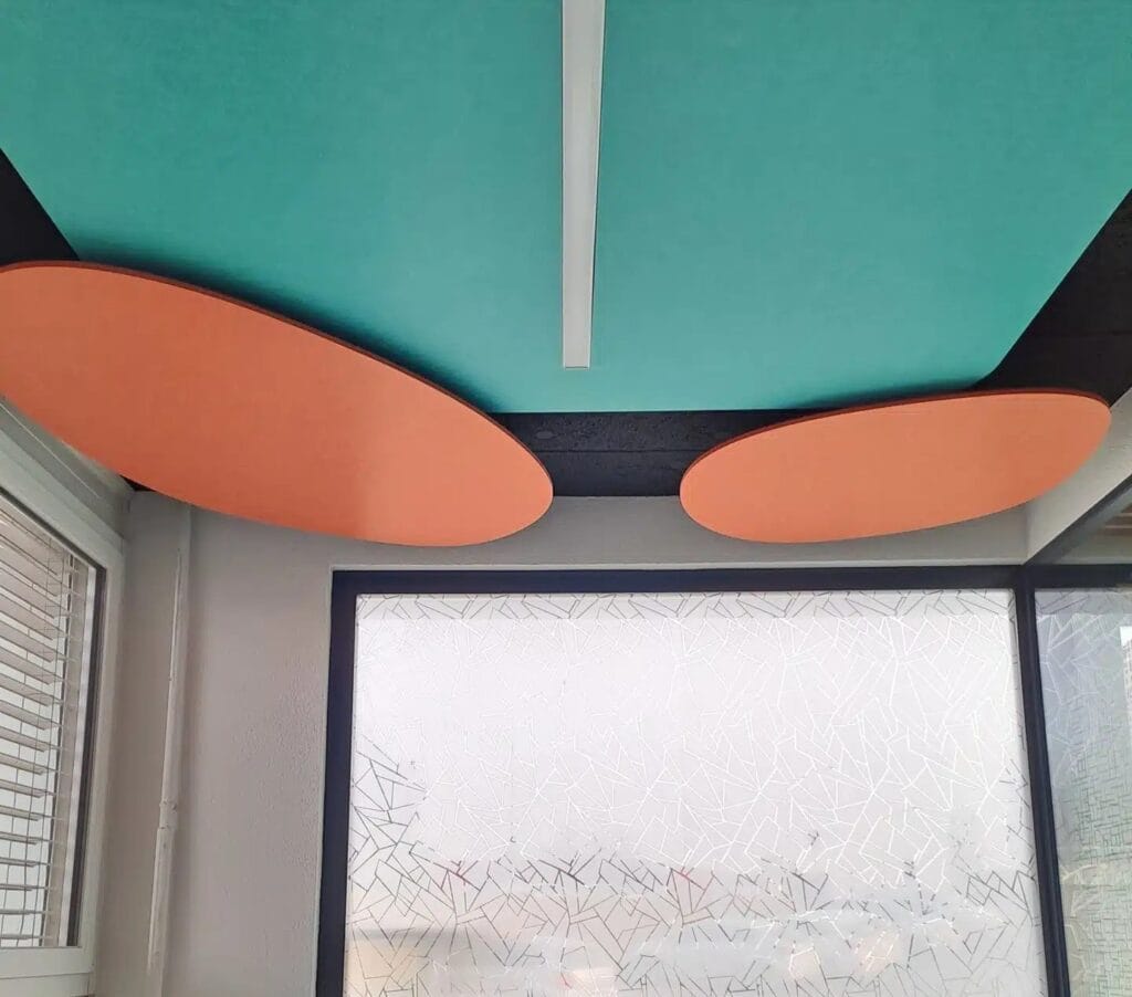 Panneaux acoustiques au plafond dans un espace de bureau moderne, avec des couleurs vives orange et turquoise pour l&rsquo;absorption du son