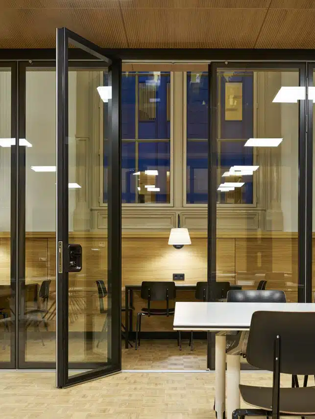 Un bureau élégant avec des cloisons en verre à cadre noir, offrant un espace de travail ouvert mais privé