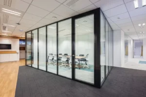 Salle de réunion transparente avec des murs en verre et des cadres noirs, permettant à la lumière naturelle de circuler dans l’espace