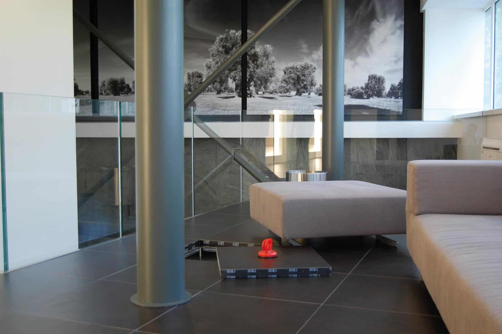 Un salon élégant avec un plancher technique surélevé, du mobilier moderne et une balustrade en verre pour un design ouvert