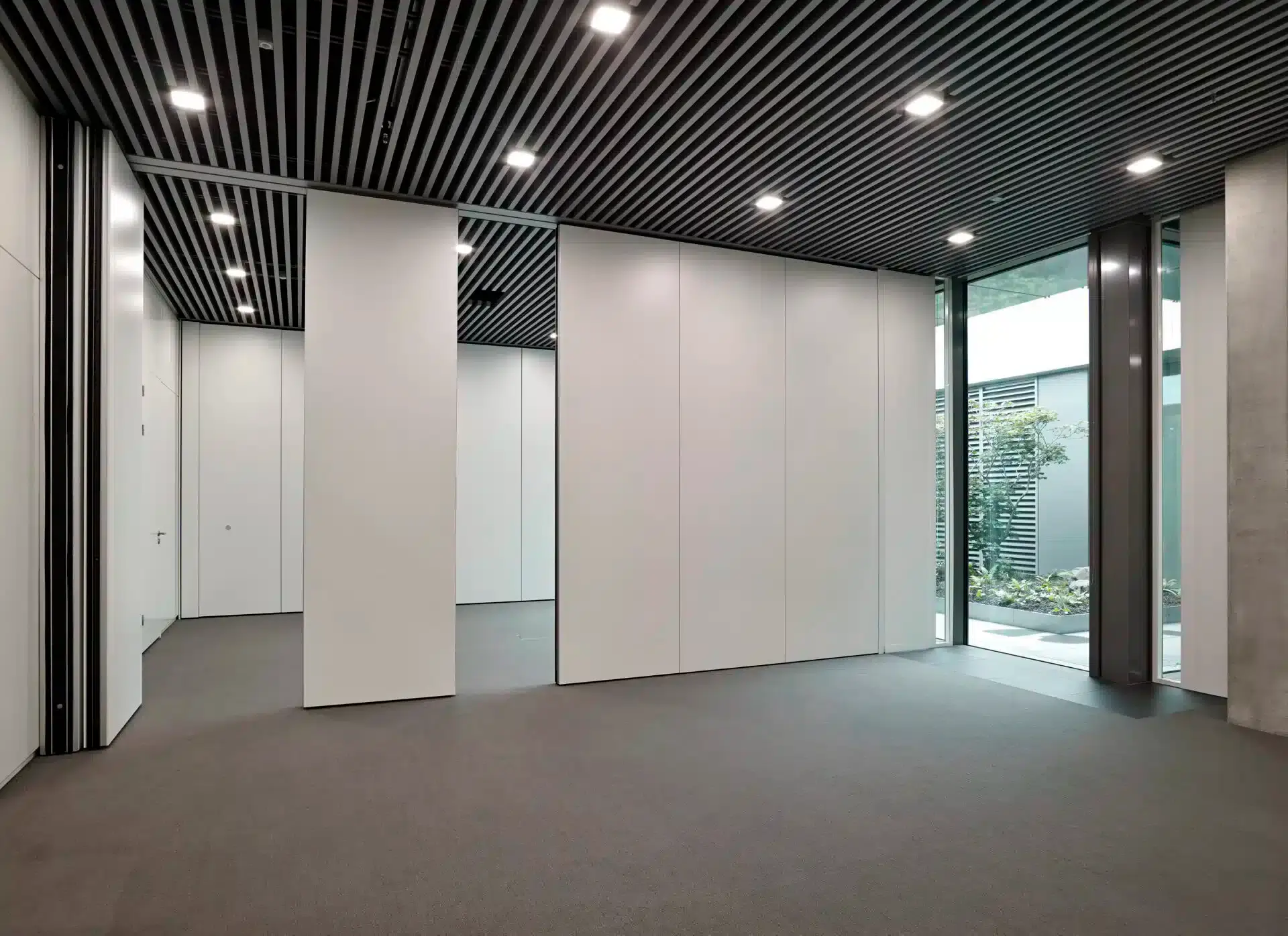 Salle avec cloisons mobiles partiellement ouvertes, permettant une disposition flexible de l'espace et une fonctionnalité améliorée