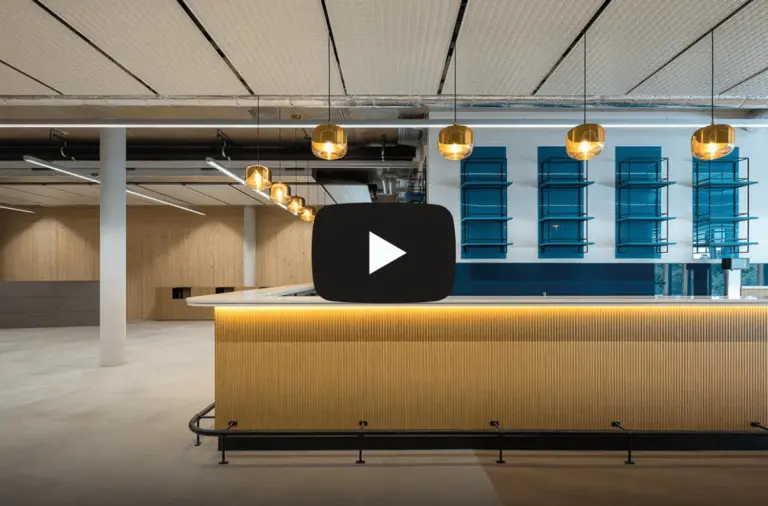 Intérieur moderne et minimaliste avec des accents de bois chaleureux et un comptoir élégant illuminé par des suspensions dorées, avec une icône de lecture pour une miniature vidéo