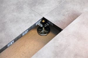 Détail d’un plancher technique en cours d’installation, avec système de plots réglables visible en dessous