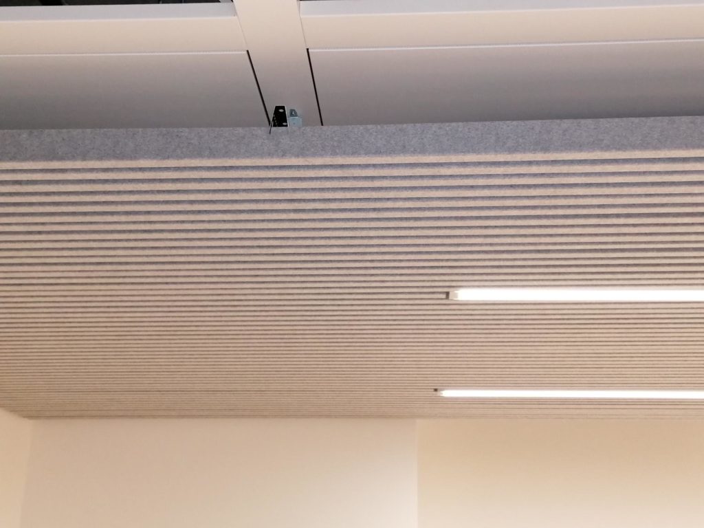 Plafond suspendu acoustique moderne avec lames linéaires et éclairage LED intégré, idéal pour l'isolation phonique et le design esthétique de bureaux.