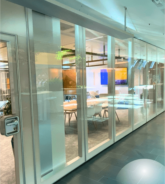 Cloison vitrée entourant une salle de réunion moderne avec table en bois et design de bureau contemporain