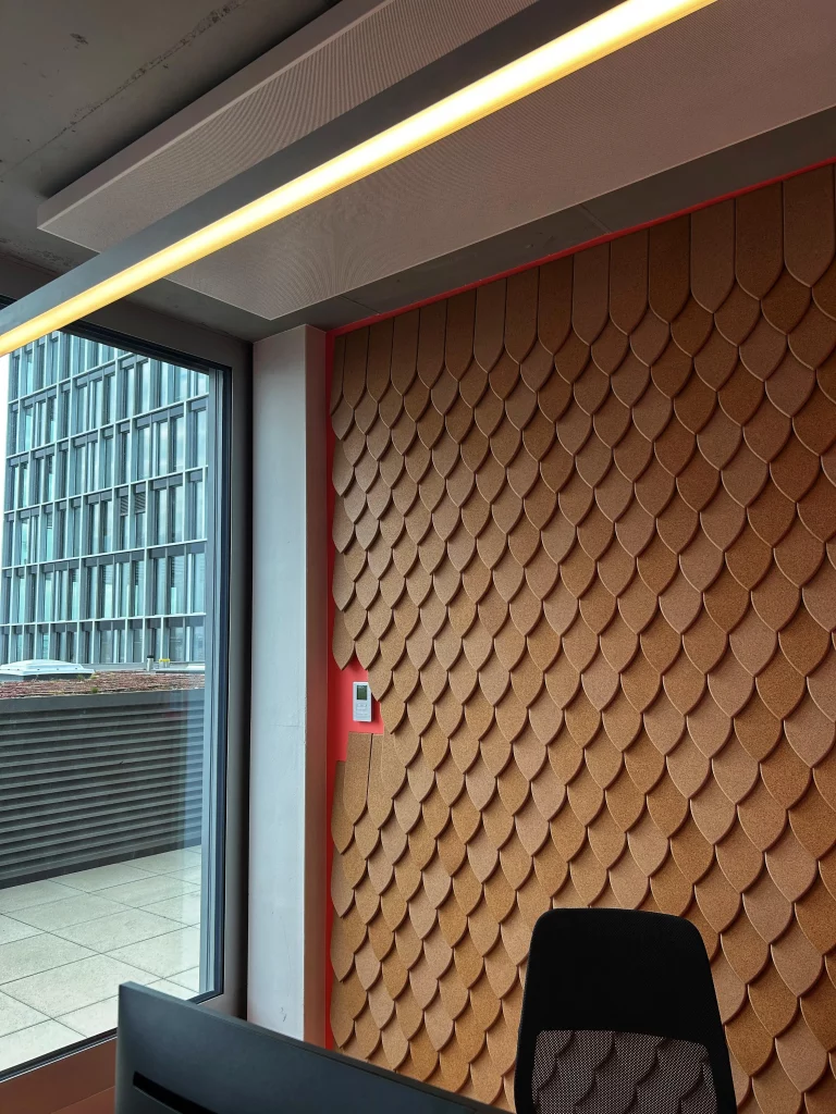 Panneaux muraux acoustiques en li&egrave;ge avec motif en &eacute;caille dans un bureau moderne pr&egrave;s d&rsquo;une grande fen&ecirc;tre
