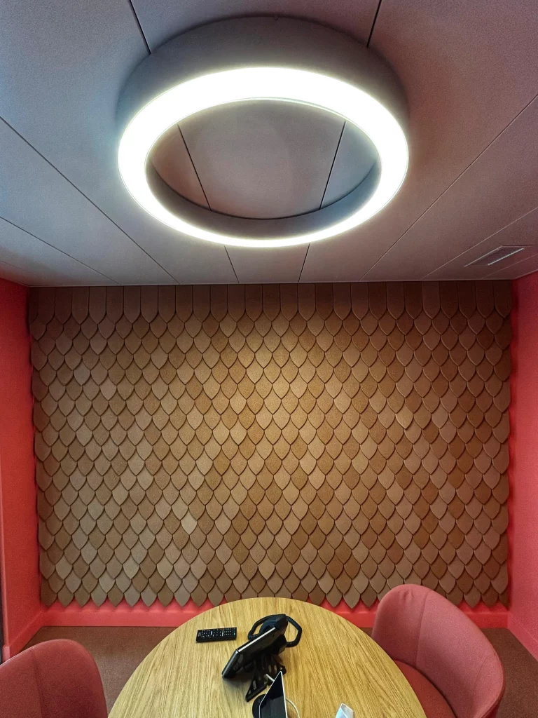 Panneaux acoustiques dans une salle de r&eacute;union moderne avec luminaire circulaire et table ronde en bois