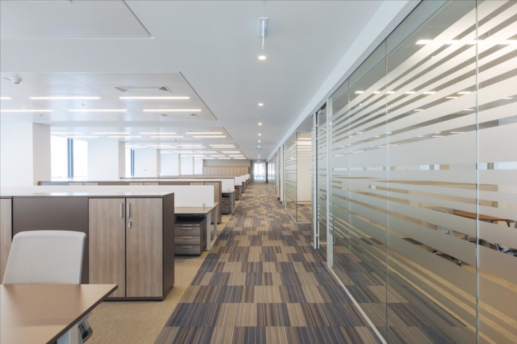 Bureau open space moderne avec cloisons vitrées à bandes dépolies, assurant intimité visuelle, confort acoustique et organisation efficace des espaces de travail