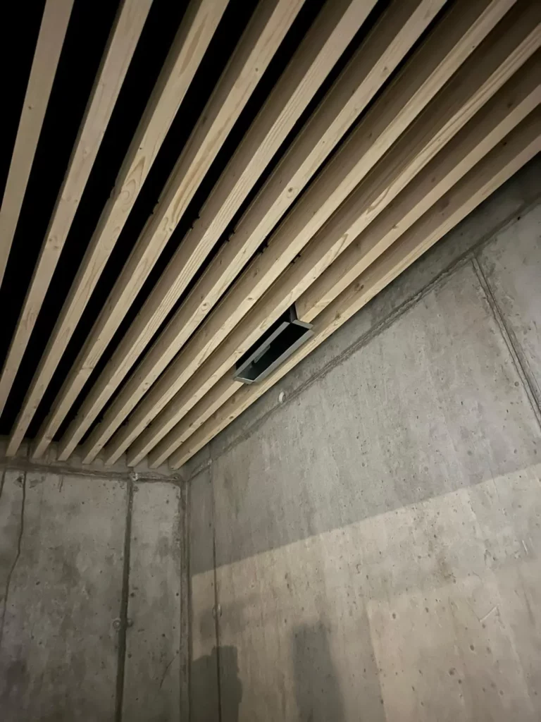 Détail d’un faux-plafond en lames de bois réalisé pour la Télécabine de Morgins, mettant en valeur l’architecture intérieure de la station.