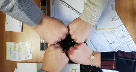 Gros plan de plusieurs mains en geste de solidarité, symbolisant le travail d’équipe et la collaboration sur un projet architectural